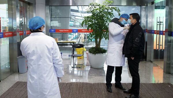 Медицинские работники измеряют температуру тела мужчины в зале вылета аэропорта в китайском городе Чанша - 俄罗斯卫星通讯社