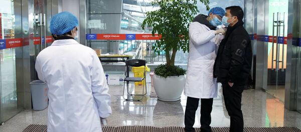 Медицинские работники измеряют температуру тела мужчины в зале вылета аэропорта в китайском городе Чанша - 俄羅斯衛星通訊社