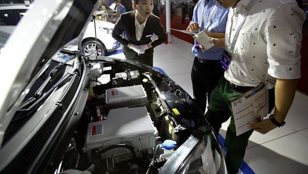 A staff member talks with visitors as they look over the motor of an iEV5 electric car from Chinese automaker JAC on display at the Beijing International Automotive Exhibition in Beijing, Monday, April 25, 2016. - 俄罗斯卫星通讯社