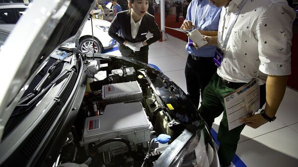 A staff member talks with visitors as they look over the motor of an iEV5 electric car from Chinese automaker JAC on display at the Beijing International Automotive Exhibition in Beijing, Monday, April 25, 2016. - 俄罗斯卫星通讯社