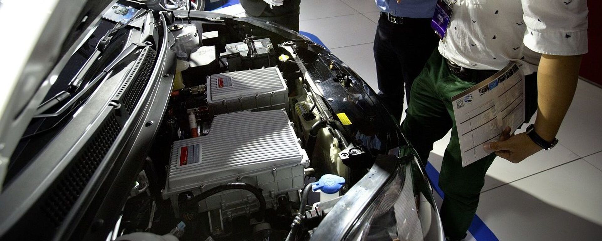 A staff member talks with visitors as they look over the motor of an iEV5 electric car from Chinese automaker JAC on display at the Beijing International Automotive Exhibition in Beijing, Monday, April 25, 2016. - 俄罗斯卫星通讯社, 1920, 02.11.2020