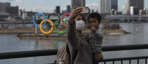 A woman takes a selfie with her son in front of the Olympic rings in Tokyo's Odaiba district. - 俄罗斯卫星通讯社
