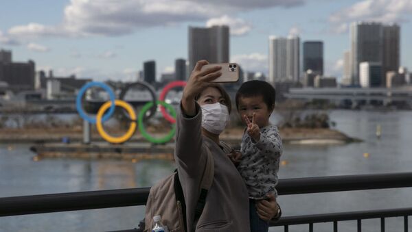 A woman takes a selfie with her son in front of the Olympic rings in Tokyo's Odaiba district. - 俄羅斯衛星通訊社