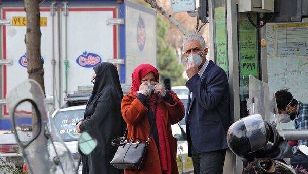 People wearing protective masks wait along the side of a street in the Iranian capital Tehran  - 俄罗斯卫星通讯社