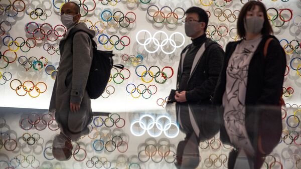 Люди в защитных масках на фоне олимпийских колец. Токио. Япония - 俄羅斯衛星通訊社