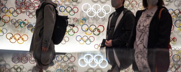 Люди в защитных масках на фоне олимпийских колец. Токио. Япония - 俄羅斯衛星通訊社
