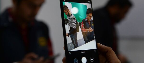 An Indian consumer holds the newly-launched Xiaomi Redmi Note 5 smartphone during a promotional event in New Delhi on February 14, 2018. - 俄罗斯卫星通讯社