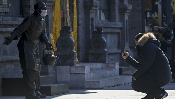 Мужчина фотографирует статую в защитной маске, Пекин - 俄罗斯卫星通讯社