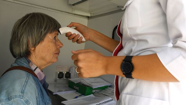 Сотрудник мобильного пункта вакцинации измеряет температуру - 俄羅斯衛星通訊社