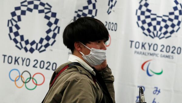 Мужчина в защитной маске на фоне флагов Олимпийских игр 2020 - 俄罗斯卫星通讯社