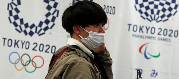 Мужчина в защитной маске на фоне флагов Олимпийских игр 2020 Мужчина в защитной маске на фоне флагов Олимпийских игр 2020 - 俄羅斯衛星通訊社