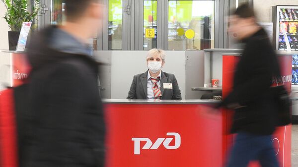 Женщина в защитной маске за стойкой информации в здании Казанского вокзала в Москве. - 俄羅斯衛星通訊社