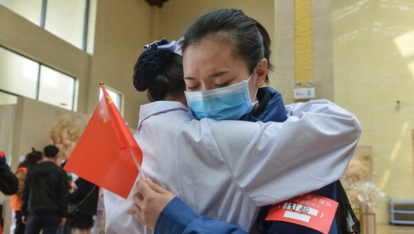 This photo taken on March 23, 2020 shows a local medical staff member (L) hugging a member of a medical assistance team - 俄羅斯衛星通訊社