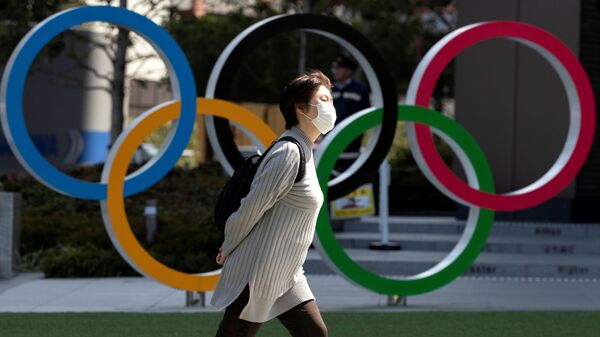 Женщина в медицинской маске напротив олимпийских колец в Токио - 俄罗斯卫星通讯社