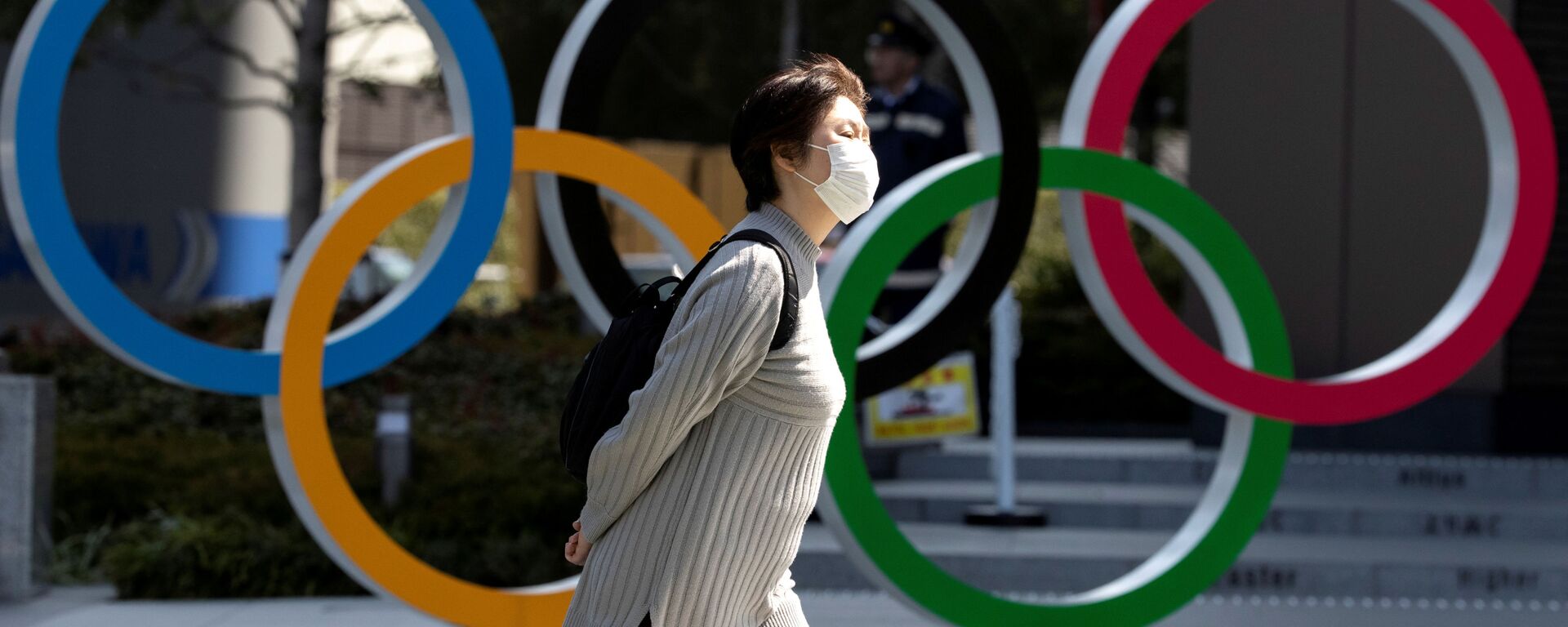 Женщина в медицинской маске напротив олимпийских колец в Токио - 俄羅斯衛星通訊社, 1920, 08.02.2021