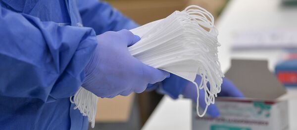 Руки в перчатках держат защитные медицинские маски - 俄罗斯卫星通讯社