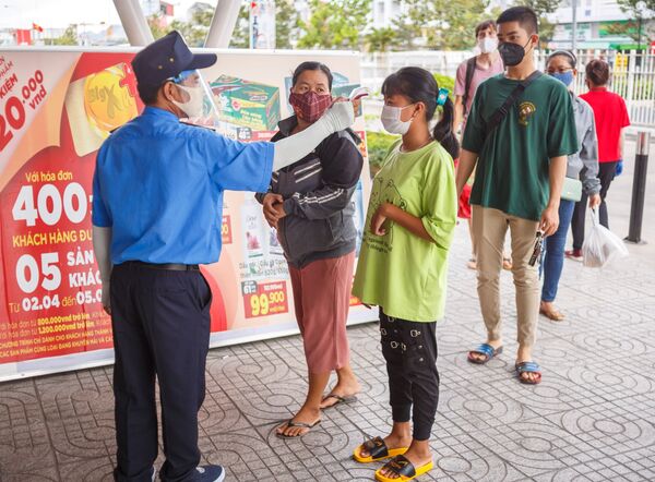 Охранник измеряет температуру у покупателя на входе в супермаркет в курортном городе Нячанг во Вьетнаме - 俄羅斯衛星通訊社