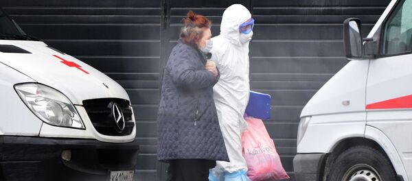 Медик скорой помощи помогает госпитализированной пациентке дойти до карантинного центра по коронавирусу в Коммунарке. - 俄羅斯衛星通訊社