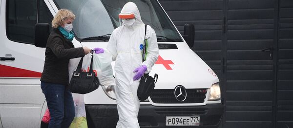 Медик скорой помощи в защитном костюме помогает пациентке донести вещи до карантинного центра в Коммунарке Медик скорой помощи в защитном костюме помогает пациентке донести вещи до карантинного центра в Коммунарке - 俄罗斯卫星通讯社