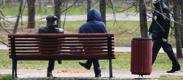 Сотрудник полиции подходит к людям, сидящим на скамейке в сквере - 俄罗斯卫星通讯社