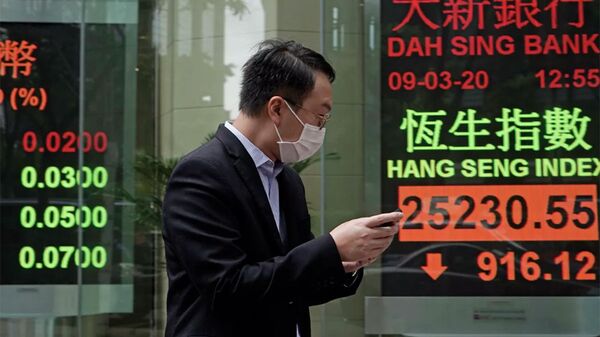 Мужчина в защитной маске на фоне табло с котировками ценных бумаг в Гонконге  - 俄羅斯衛星通訊社