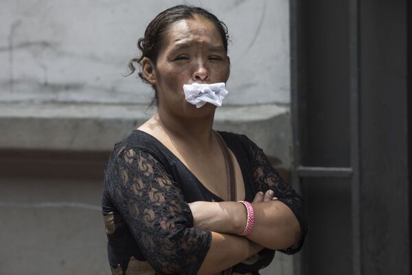 Женщина держит бумагу во рту, как альтернативу маске, в очереди бесплатный обед для бездомных в Лиме, ​​Перу - 俄羅斯衛星通訊社