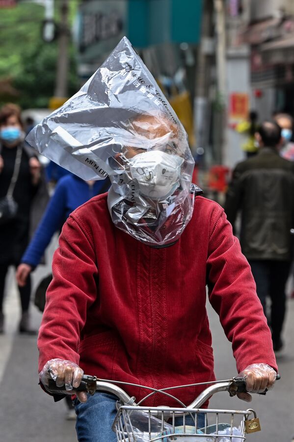 Велосипедист в защитной маске и с пластиковым пакетом на голове на одной из улиц Уханя, Китай - 俄羅斯衛星通訊社