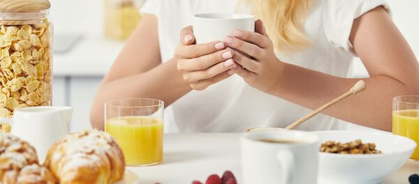 Женщина с чашкой кофе и завтраком на столе Женщина с чашкой кофе и завтраком на столе - 俄罗斯卫星通讯社