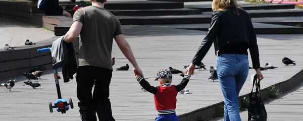 Семейная пара с ребенком гуляют по набережной Семейная пара с ребенком гуляют по набережной - 俄罗斯卫星通讯社
