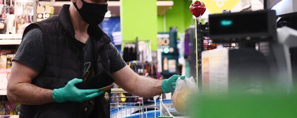 Покупатель в защитной маске и резиновых перчатках на кассе в продуктовом магазине в Москве - 俄羅斯衛星通訊社