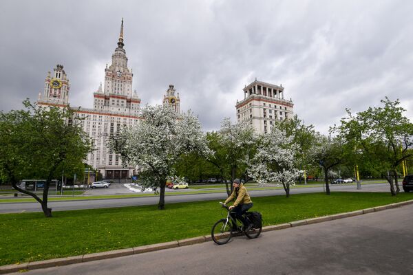 Велосипедист на фоне цветущих деревьев у здания МГУ в Москве - 俄羅斯衛星通訊社
