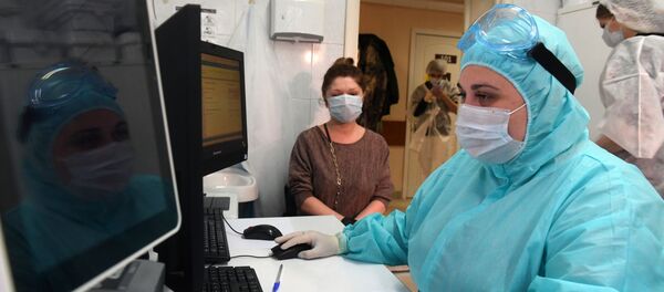 Медицинский работник в защитном костюме регистрирует посетителя для сдачи анализа на наличие антител к COVID-19 в городской поликлинике Москвы - 俄罗斯卫星通讯社