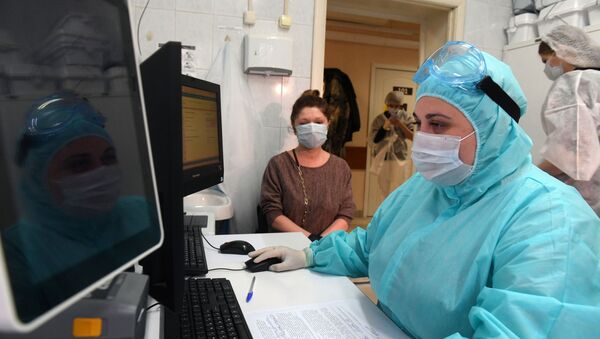 Медицинский работник в защитном костюме регистрирует посетителя для сдачи анализа на наличие антител к COVID-19 в городской поликлинике Москвы - 俄羅斯衛星通訊社