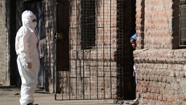 Женщина в защитном костюме разговаривает с ребенком в районе проживания мигрантов после объявления карантина в Сантьяго, Чили  - 俄罗斯卫星通讯社