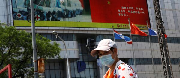 A pedestrian wearing a face mask walks past a screen showing an image of Chinese People's Liberation Army - 俄罗斯卫星通讯社