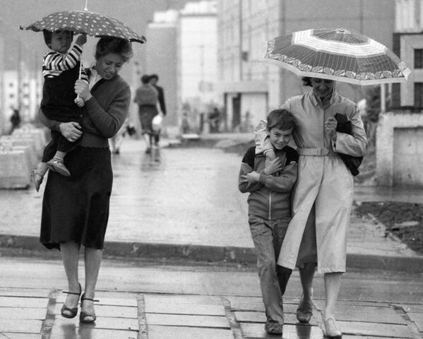 Прохожие идут по улице, прячась от дождя под зонтом - 俄罗斯卫星通讯社