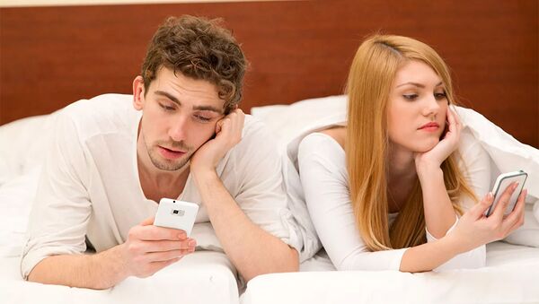 Молодая пара со сматфонами в кровати - 俄罗斯卫星通讯社