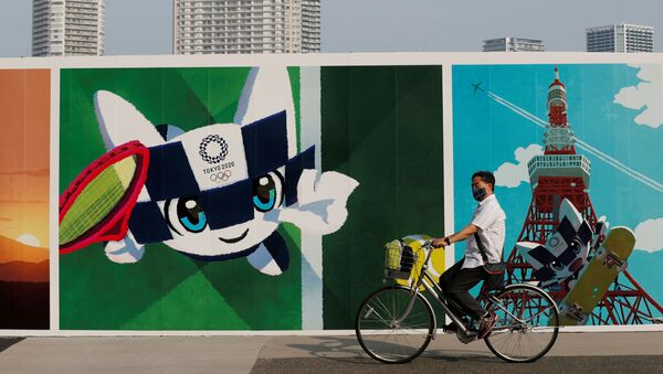 Мужчина на велосипеде проезжает мимо граффити на тему олимпийских игр в Японии - 俄罗斯卫星通讯社