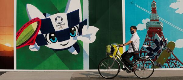 Мужчина на велосипеде проезжает мимо граффити на тему олимпийских игр в Японии - 俄羅斯衛星通訊社