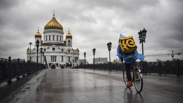 Курьер, доставляющий еду, на велосипеде у Храма  Христа Спасителя в центре Москвы - 俄罗斯卫星通讯社