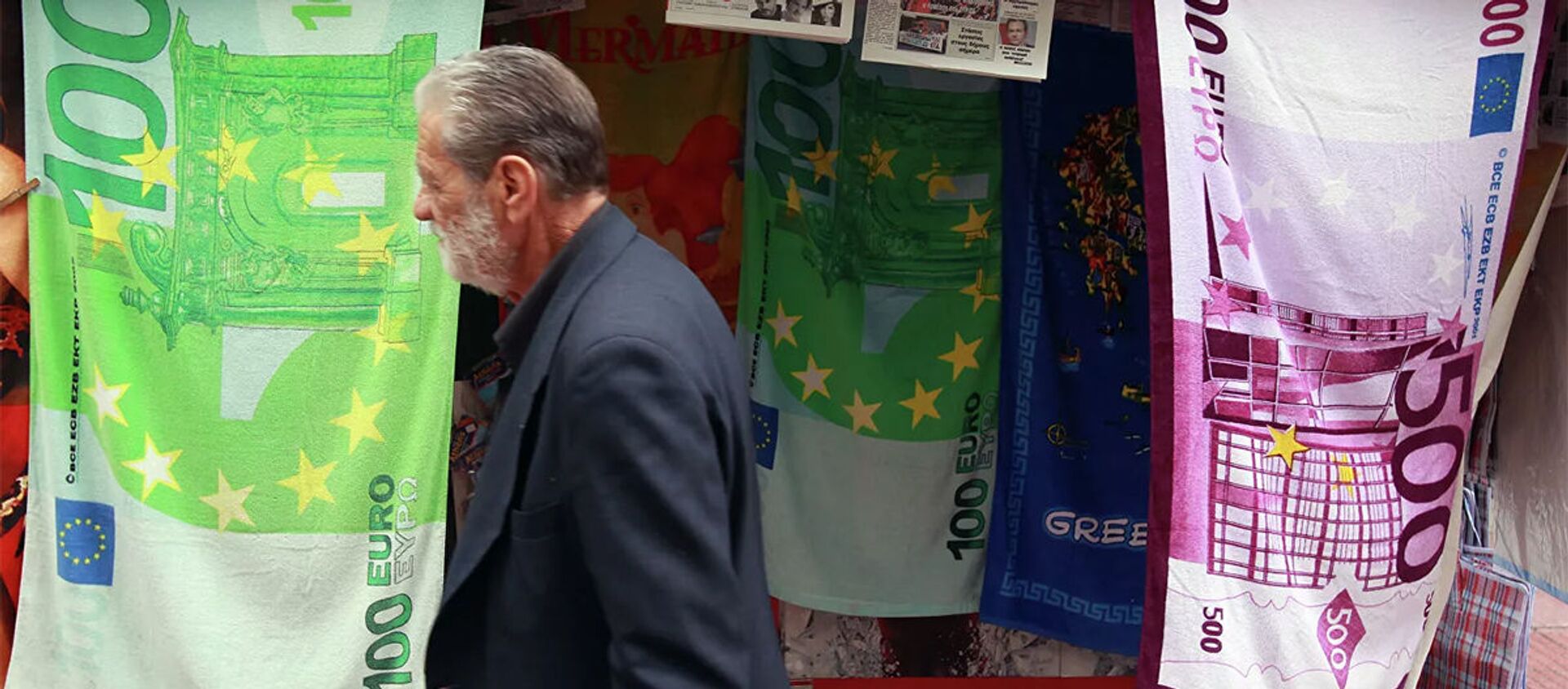 Мужчина проходит мимо киоска, торгующего полотенцами в виде банкнот евро в Греции. - 俄罗斯卫星通讯社, 1920, 07.02.2021