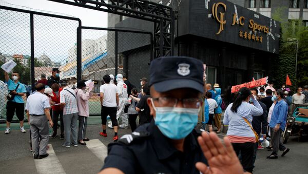 Охранник в маске пытается заблокировать камеру возле спортивного центра Guangan, где проводят тестирование на коронавирус в Пекине  - 俄羅斯衛星通訊社