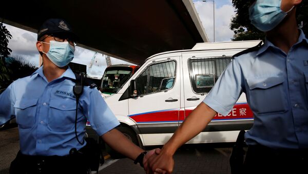 Police officers escort a prison van which is carrying Tong Ying-kit, the first person charged under the new national security law, as he leaves West Kowloon Magistrates' Courts, in Hong Kong, China July 6, 2020.  - 俄罗斯卫星通讯社